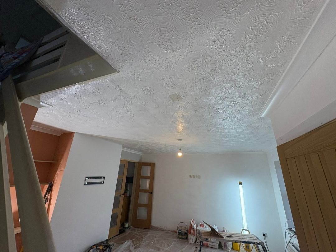 Before: A swirl-textured ceiling, the floor sheeted and plaster bags in, before work starts.